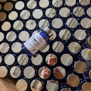 May include: A close-up of numerous blue supplement bottles with silver lids. One bottle is in focus, labelled "LiverMD" and "IMD Nutrition". The bottles are densely packed, indicating a large quantity.
