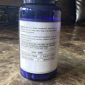 May include: A blue supplement bottle with a silver lid. The label states the product is non-GMO, and free of shellfish, peanuts, dairy, and wheat. The bottle contains blue capsules and is on a marble surface.