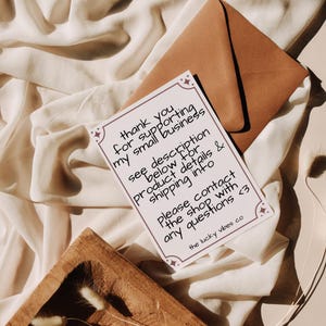Pode incluir: Um cart&atilde;o retangular branco com uma borda roxa escura e detalhes de estrelas, contendo o texto: thank you for supporting my small business, see description below for product details & shipping info, please contact the shop with any questions <3, the lucky vibes co.