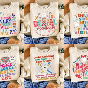 Puede incluir: Sudaderas color crema con gráficos coloridos con temática dental. Los diseños incluyen texto como "Detrás de cada sonrisa segura hay un asistente dental" y "Los asistentes dentales hacen que las sonrisas sucedan".