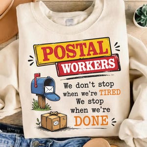 May include: A cream-colored crewneck sweatshirt featuring a graphic with the text POSTAL WORKERS in yellow and red boxes. Below, a blue mailbox and a brown package are illustrated alongside the text: We don't stop when we're TIRED We stop when we're DONE.