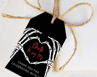 Puede incluir: Etiqueta de regalo negra con un corazón de manos de esqueleto y el texto "Death to my 20's". La etiqueta también incluye el texto "Thank you for celebrating with me". La etiqueta está atada con hilo.