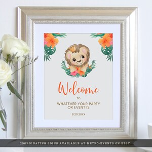 May include: Framed welcome sign with a cartoon lion wearing a crown, surrounded by tropical flowers and leaves. The sign says "Welcome" in orange script, with space to add party details. The frame is silver.