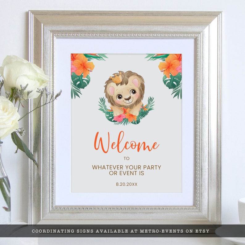 May include: Framed welcome sign with a cartoon lion wearing a crown, surrounded by tropical flowers and leaves. The sign says "Welcome" in orange script, with space to add party details. The frame is silver.