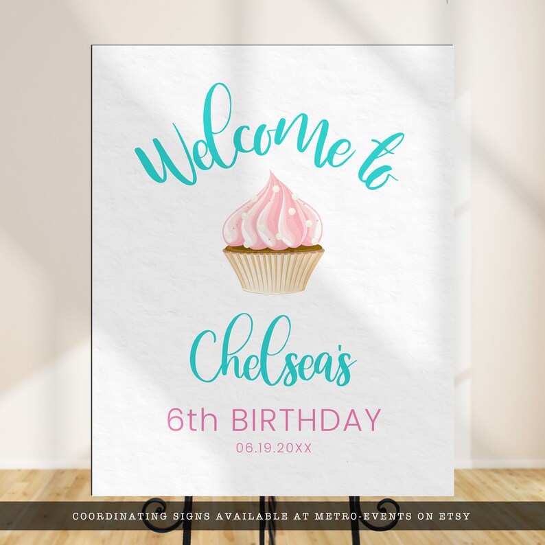 May include: A white sign with the words "Welcome to" in teal script above a pink cupcake with white polka dots. Below the cupcake, the sign reads "Chelsea's 6th BIRTHDAY" with the date 06.19.20XX.
