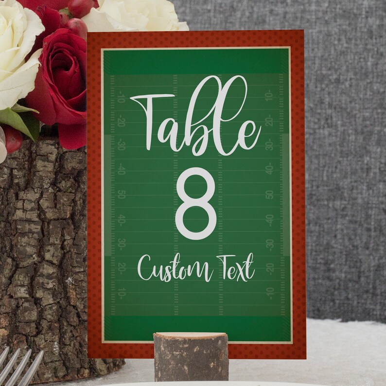 May include: A rectangular table number card featuring a green football field design with yard line markings. The card displays the white text Table 8 and Custom Text in a script font, surrounded by a red border with a subtle polka dot pattern.