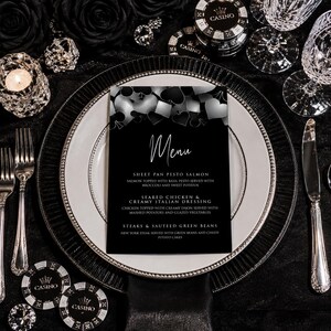 May include: A black and white menu card featuring a top border of playing card suit symbols including hearts, diamonds, clubs, and spades. The text reads Menu, Sheet Pan Pesto Salmon, Seared Chicken & Creamy Italian Dressing, and Steaks & Sauteed Green Beans.