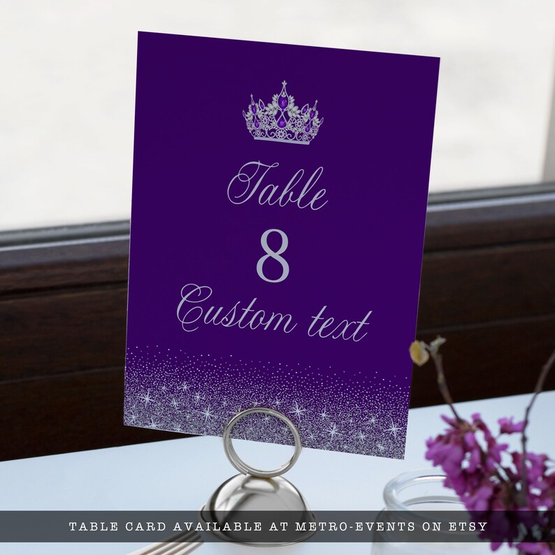 A glam style sweet sixteen and quinceanera table number. This glittery design is created with faux silver glitter on a purple background and a princess crown. Designed by MetroEvents.