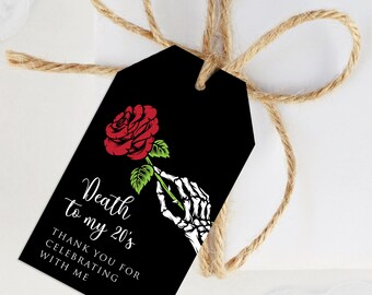 Puede incluir: Etiqueta de regalo negra con una rosa roja sostenida por una mano esquelética. La etiqueta dice "Death to my 20's" y "Thank you for celebrating with me" en escritura blanca. La etiqueta está atada con cuerda.
