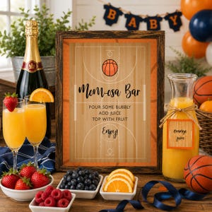 May include: A framed sign with a basketball court design and the text Mom-osa Bar, Pour some bubbly, Add juice, Top with fruit, Enjoy. The sign is surrounded by a bottle of champagne, two glasses of orange juice, bowls of berries, and orange slices.