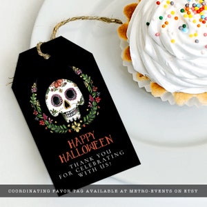 Day of the dead themed favor tag a watercolor-style sugar skull with flower and leaf accents on a black background. Designed By MetroEvents