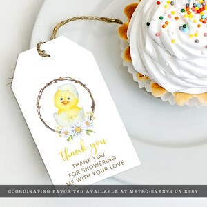 May include: White gift tag with a watercolor illustration of a yellow chick hatching from an egg, surrounded by a wreath and daisies. The tag reads "thank you" in gold script, with additional text below. A cupcake with white frosting is in the background.