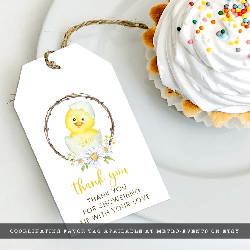 May include: White gift tag with a watercolor illustration of a yellow chick hatching from an egg, surrounded by a wreath and daisies. The tag reads "thank you" in gold script, with additional text below. A cupcake with white frosting is in the background.