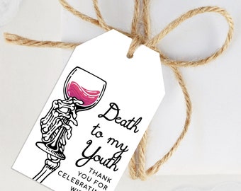 Puede incluir: Etiqueta de regalo blanca con una mano de esqueleto sosteniendo una copa de vino llena de líquido rojo. La etiqueta dice "Death to my Youth" y "Thank you for celebrating with me". Atada con cuerda.