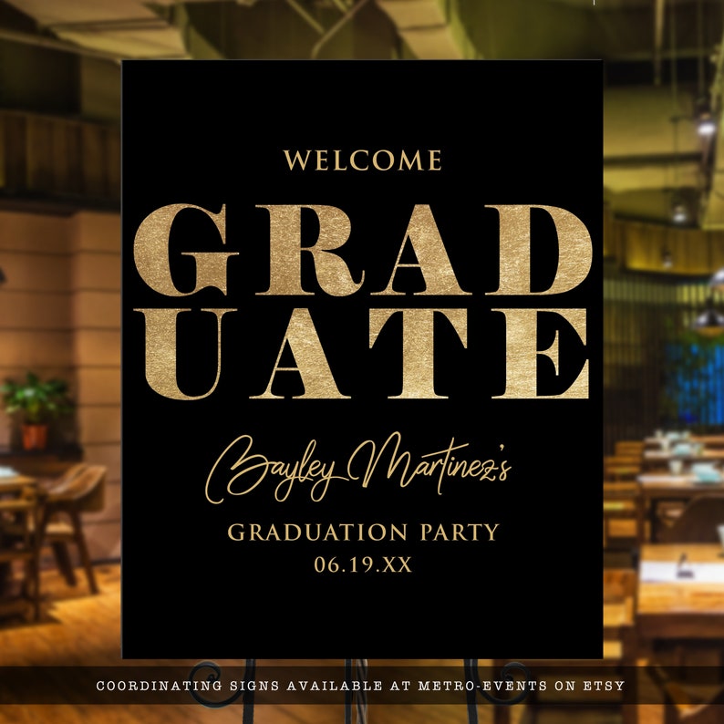 May include: A black graduation party sign with gold text. The sign reads "WELCOME GRADUATE Bayley Martinez's GRADUATION PARTY 06.19.XX". The sign is displayed on a metal stand.