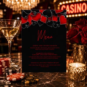 May include: A black menu card with red text and a top border of red and black playing card suit symbols. The menu lists Sheet Pan Pesto Salmon, Seared Chicken and Creamy Italian Dressing, and Steaks and Sauteed Green Beans in a casino setting.