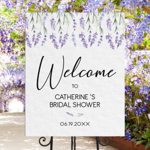 May include: A white sign with a lavender floral border and the text "Welcome to Catherine's Bridal Shower 06.19.20XX".