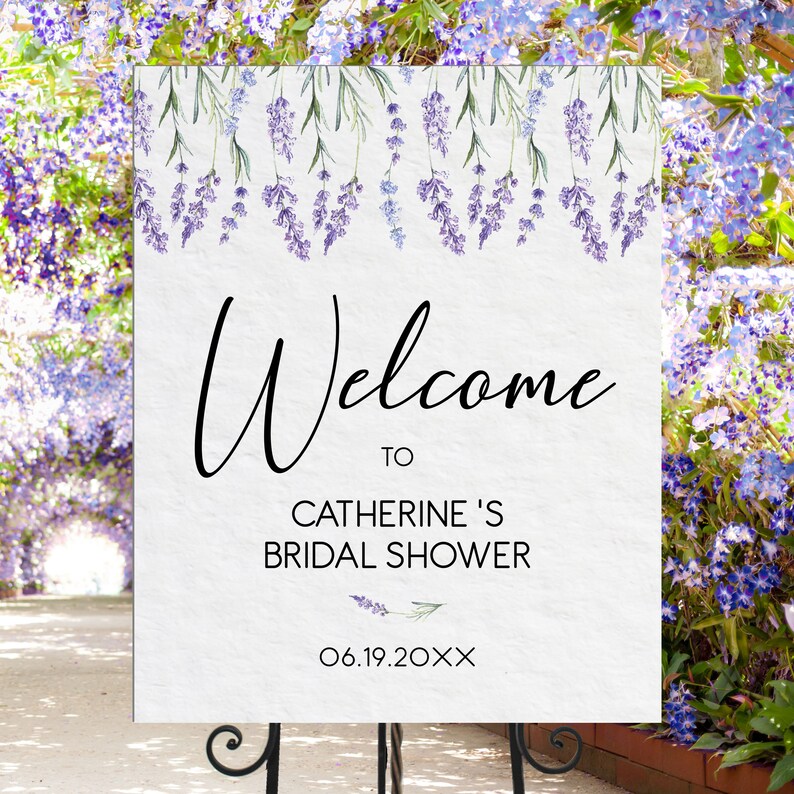 May include: A white sign with a lavender floral border and the text "Welcome to Catherine's Bridal Shower 06.19.20XX".