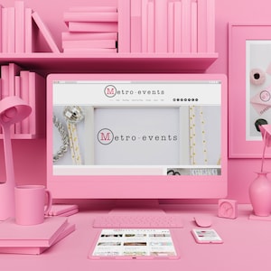 May include: A pink computer setup with a monitor displaying the "Metro-Events" website. The desk includes a keyboard, mouse, tablet, and smartphone. A pink lamp, mug, and books are also visible, along with a shelf of pink books.