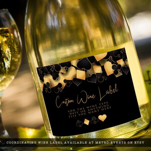 May include: A clear glass wine bottle featuring a black rectangular label with gold and black playing card suit symbols. The label displays the text Custom Wine Label, followed by ADD THE WINE TYPE, DATE OR ANYTHING ELSE YOU WANT HERE.