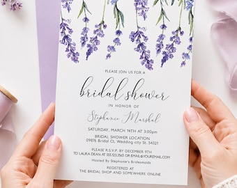 May include: A white bridal shower invitation with watercolor lavender sprigs. The invitation includes the text "Please join us for a bridal shower in honor of Stephanie Marshal" and event details. The invitation is held in a lavender envelope.