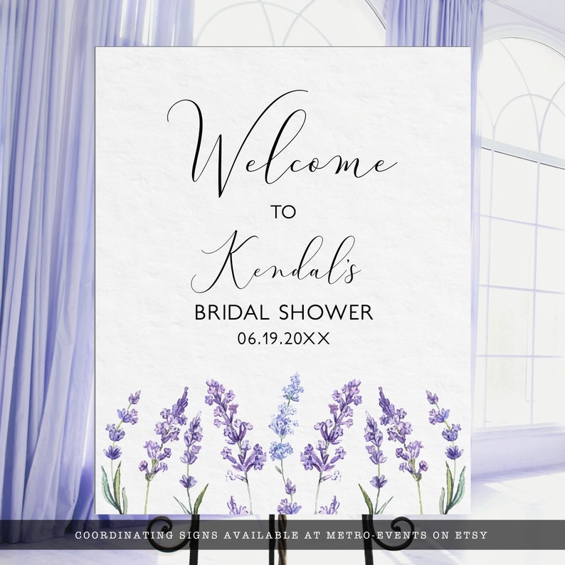 Pu&ograve; includere: Un cartello di benvenuto bianco con testo nero che recita "Benvenuti a Kendal's Bridal Shower 06.19.20XX". Il cartello &egrave; decorato con un bordo di fiori di lavanda viola e blu.