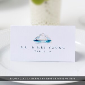 K&ouml;nnte beinhalten: Eine wei&szlig;e Begleitkarte mit einer Illustration eines blauen und wei&szlig;en Segelboots. Der Text "MR. & MRS YOUNG TABLE 19" ist in Blau gedruckt.