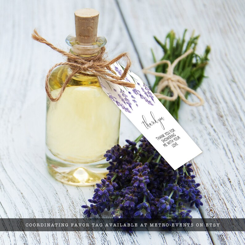 May include: A clear glass bottle with a cork stopper, filled with yellow liquid, and tied with twine. A white tag with lavender sprigs and the words "thank you" hangs from the bottle. A bundle of purple lavender and greenery are also present.