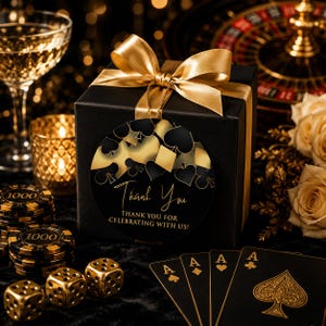 May include: A black square gift box tied with a gold satin ribbon, featuring a circular tag with gold and black playing card suit symbols and the text Thank You and THANK YOU FOR CELEBRATING WITH US in a gold script and sans-serif font.