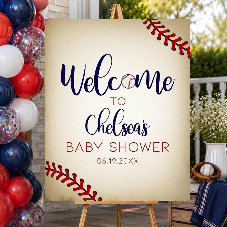 May include: A baseball-themed baby shower welcome sign on a wooden easel. The sign features the words "Welcome to Chelsea's Baby Shower" in navy and red, with baseball stitching accents. Balloons in red, white, and blue are on the left.