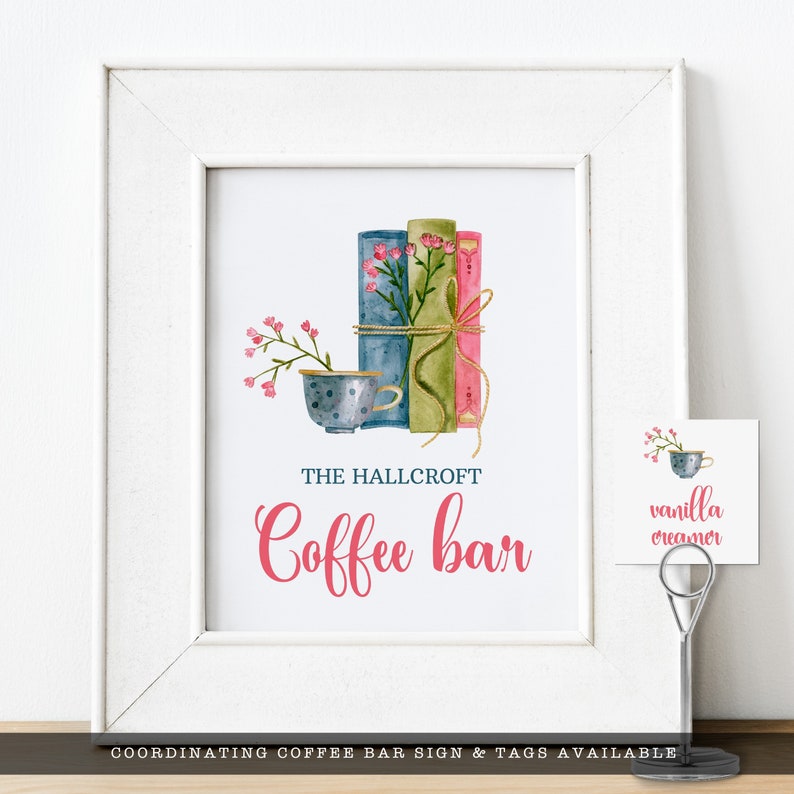 May include: A white framed print featuring a watercolor illustration of three stacked books in blue, green, and pink, tied with twine and topped with pink flowers next to a polka-dot teacup. The text reads THE HALLCROFT Coffee bar.