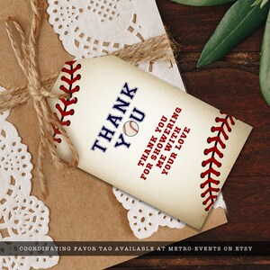 Puede incluir: Una etiqueta de regalo rectangular de papel con fondo crema y costuras rojas estilo b&eacute;isbol en los bordes. El texto dice THANK YOU con un gr&aacute;fico de pelota de b&eacute;isbol, seguido de THANK YOU FOR SHOWERING ME WITH YOUR LOVE en azul y rojo.