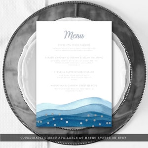 May include: A white menu card with a watercolor wave design in shades of blue and silver dots. The word "Menu" is written in a script font. The menu lists several dishes, including salmon, chicken, steak, and tofu. The text "COORDINATING MENU AVAILABLE AT METRO-EVENTS ON ETSY" is at the bottom.