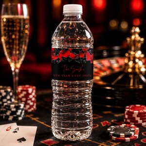 May include: A clear plastic water bottle with a white cap and a black label featuring red and black playing card suit symbols. The label text reads The Smith's NEW YEAR'S EVE PARTY in a red script and white sans-serif font on a black background.