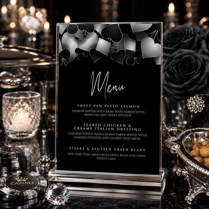 May include: A vertical rectangular menu card in a clear acrylic stand featuring a black background with silver playing card suit icons at the top. The text reads Menu, Sheet Pan Pesto Salmon, Seared Chicken & Creamy Italian Dressing, and Steaks & Sauteed Green Beans.