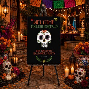 May include: A black rectangular sign on a tripod stand featuring the text WELCOME FOOLISH MORTALS, a central white sugar skull illustration with colorful floral details, and the text THE SANDERS' HALLOWEEN PARTY 10.31.20XX with a green leaf border.