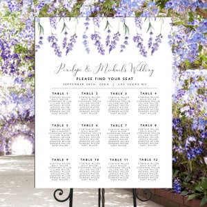 May include: A wedding seating chart with a lavender floral design. The names of the bride and groom are at the top, followed by the words "Please Find Your Seat" and the wedding date and location. The names are organized by table number.