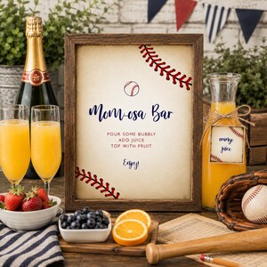 K&ouml;nnte beinhalten: Ein rechteckiger Holzrahmen mit einem Schild, das den Text Mom-osa Bar, Pour some bubbly, Add juice, Top with fruit und Enjoy enth&auml;lt. Das Schild zeigt Baseball-Grafiken, darunter einen Baseball und rote Nahtmuster auf einem cremefarbenen Hintergrund.