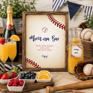 K&ouml;nnte beinhalten: Ein gerahmtes Schild mit Baseball-Motiv mit der Aufschrift Mom-osa Bar, Pour some bubbly, Add juice, Top with fruit, Enjoy. Das Schild zeigt rote Baseball-Nahtgrafiken und ein Baseball-Symbol, pr&auml;sentiert mit Orangensaft, Obst und Baseball-Ausr&uuml;stung.