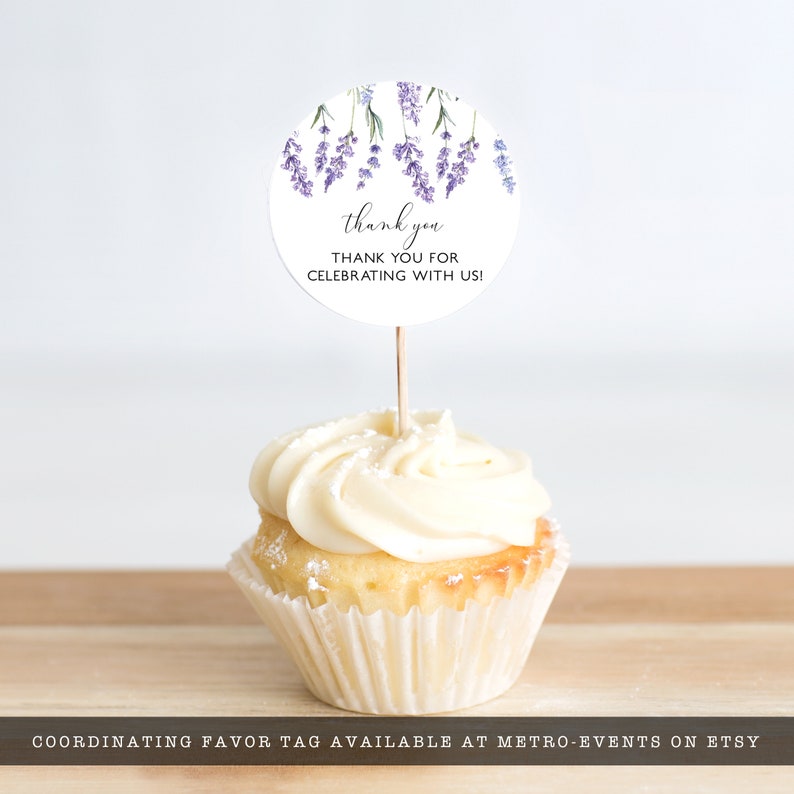 May include: A white cupcake with vanilla frosting topped with a round lavender-themed thank you tag. The tag says "thank you" and "THANK YOU FOR CELEBRATING WITH US!"