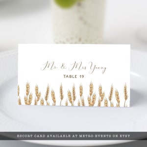 May include: A white escort card with the text "Mr. & Mrs Young" and "TABLE 19" in brown script. The card is decorated with a row of wheat stalks at the bottom.