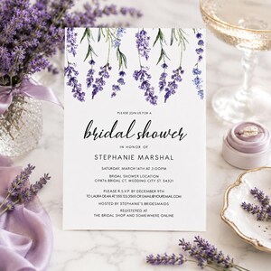May include: A white rectangular bridal shower invitation card featuring a watercolor illustration of purple lavender sprigs at the top. The text reads: Please join us for a bridal shower in honor of Stephanie Marshal, Saturday, March 14th at 3:00PM.