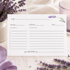May include: A white rectangular recipe card featuring a lavender sprig illustration in the top right corner. The card includes printed lines and labels for recipe, servings, cook time, time, ingredients with checkboxes, instructions, and from the kitchen of.
