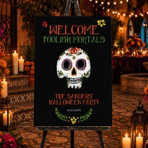 May include: A black rectangular sign on an easel featuring the text WELCOME FOOLISH MORTALS, THE SANDERS' HALLOWEEN PARTY, and 10.31.20XX. The sign displays a central white sugar skull with colorful floral details and a green leaf garland at the bottom.