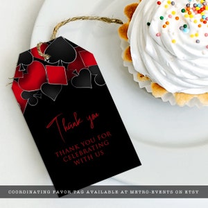 May include: A rectangular black gift tag with a twine string featuring a red and black playing card suit pattern at the top. The text reads Thank you and THANK YOU FOR CELEBRATING WITH US in red font. The tag is positioned next to a cupcake.