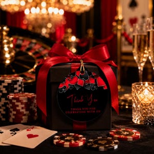May include: A black square gift box wrapped with a wide red satin ribbon and a large bow. A round black gift tag features red and black playing card suit icons and the text Thank You, THANK YOU FOR CELEBRATING WITH US, in red and white.