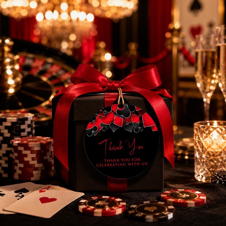 May include: A black square gift box wrapped with a wide red satin ribbon and a large bow. A round black gift tag features red and black playing card suit icons and the text Thank You, THANK YOU FOR CELEBRATING WITH US, in red and white.