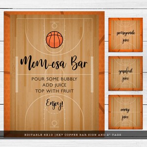 May include: A basketball court themed sign and three smaller tags with a wood grain background. The large sign features a basketball graphic and the text Mom-osa Bar, Pour some bubbly, Add juice, Top with fruit, Enjoy. The tags read pomegranate juice, grapefruit juice, and orange juice.