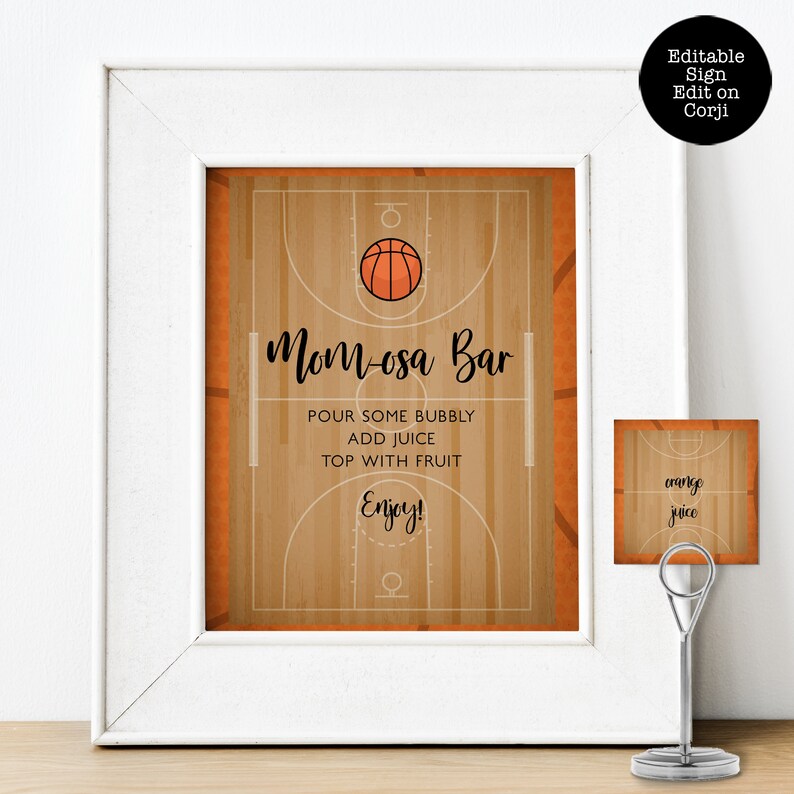 May include: A white framed sign featuring a basketball court graphic with an orange basketball and the text Mom-osa Bar, Pour some bubbly, Add juice, Top with fruit, Enjoy. A smaller matching card sits in a silver metal stand labeled orange juice.