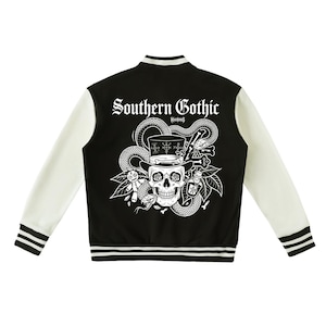 以下が含まれることがあります： 背面に「Southern Gothic」の文字が入ったグラフィックが施された、黒と白のバーシティジャケット。シルクハットを被った頭蓋骨、とぐろを巻いた蛇、ブードゥー人形、小瓶、骨が白い線画で描かれています。